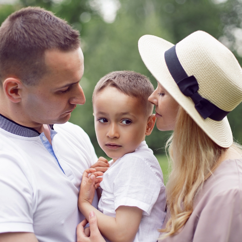 portrait family with a son standing in a grassy field